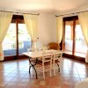 Sala da pranzo con tavolo bianco e grandi finestre.