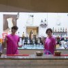 Due persone in maglia rosa dietro un bancone di bar.