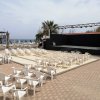 Arena all'aperto con sedie bianche e palco, vista mare.