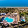 Veduta aerea di hotel con piscina vicino al mare.