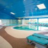Piscina interna con soffitto blu e sdraio verdi.