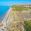 Spiaggia con ombrelloni e mare azzurro dall'alto.