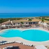 Piscina a forma di fagiolo con vista mare e lettini.