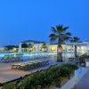 Piscina illuminata di notte con lettini e palme.