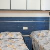 Due letti singoli con testiera blu e lenzuola con motivi floreali gialli e grigi.