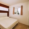Camera da letto con parete rossa, letto matrimoniale e finestra con tende beige.
