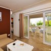 Soggiorno con divano beige, tavolino e accesso alla terrazza con tavolo da pranzo.