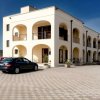 Edificio con archi e balconi, auto parcheggiate davanti.