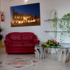 Salotto con divano rosso, piante e quadro luminoso sul muro.