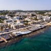 Veduta aerea di una città costiera con edifici bianchi e un mare turchese.