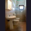 Un bagno con lavabo, bidet e cabina doccia. Pareti beige e finestra in alto.