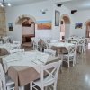 Interno di un ristorante con tavoli apparecchiati, sedie bianche e decorazioni alle pareti.