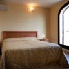 Camera con letto matrimoniale, copriletto beige decorato, grande finestra ad arco.