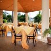 Ristorante all'aperto con colonne, tavoli apparecchiati e vista sul giardino.