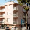 Edificio rosa con balconi e due auto parcheggiate.