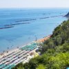 Spiaggia affollata vista dall'alto con mare calmo.