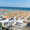 Una spiaggia con numerosi ombrelloni a righe colorate.