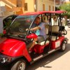 Persona alla guida di un carrello da golf rosso in una strada.