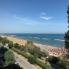 Spiaggia vista dall'alto con mare e ombrelloni.