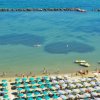 Spiaggia con ombrelloni colorati e mare calmo.