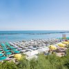 Spiaggia affollata con ombrelloni gialli e blu.