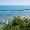 Spiaggia con ombrelloni verdi e blu e mare calmo.