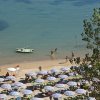 Spiaggia vista dall'alto con ombrelloni a righe e una barca.
