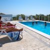 Persone su lettini vicino a una piscina.