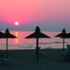 Tramonto al mare con ombrelloni neri sulla spiaggia.