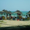 Spiaggia con ombrelloni di paglia e persone al mare.