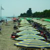 Spiaggia affollata con ombrelloni a righe multicolori.