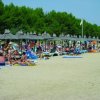 Spiaggia con lettini sotto ombrelloni di paglia.