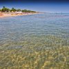 Acqua limpida davanti a una spiaggia affollata.