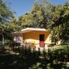 Bungalow giallo con porta rossa, giardino.