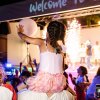 Bambina sulle spalle di un adulto a un evento festivo.