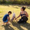 Donna e bambino con cane su prato.