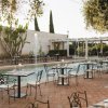 Patio esterno con tavoli e sedie vicino a una piscina.