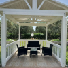 Un gazebo bianco con mobili neri in un giardino verde.