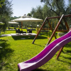 Scivolo rosa in un parco giochi con sedie e ombrelloni.