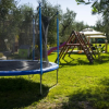 Giardino con trampolino blu, scivolo viola e altalena tra gli alberi.
