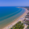 Vista aerea di una lunga spiaggia sabbiosa con ombrelloni lungo la costa.