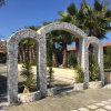 Archi di pietra, piante e palme sotto un cielo limpido.