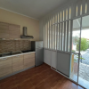 Cucina compatta con armadietti chiari e frigorifero.