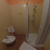 Bagno con doccia, bidet e piastrelle beige a mosaico sulle pareti.