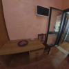 Scrivania di legno con sedia, TV a muro e porta finestra.
