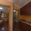 Corridoio con vista su camera da letto e bagno. Cucina con mobili in legno scuro.