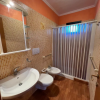 Bagno con doccia, lavabo, WC e bidet, pareti mosaico arancioni.