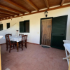 Una veranda con tavolo e sedie in legno, pavimento piastrellato e pareti bianche.
