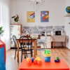 Spazio colorato con giochi per bambini, tavolo, sedie e angolo cucina. Decorazioni vivaci e piante.