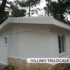 Villino bianco con base in pietra in un'area alberata.